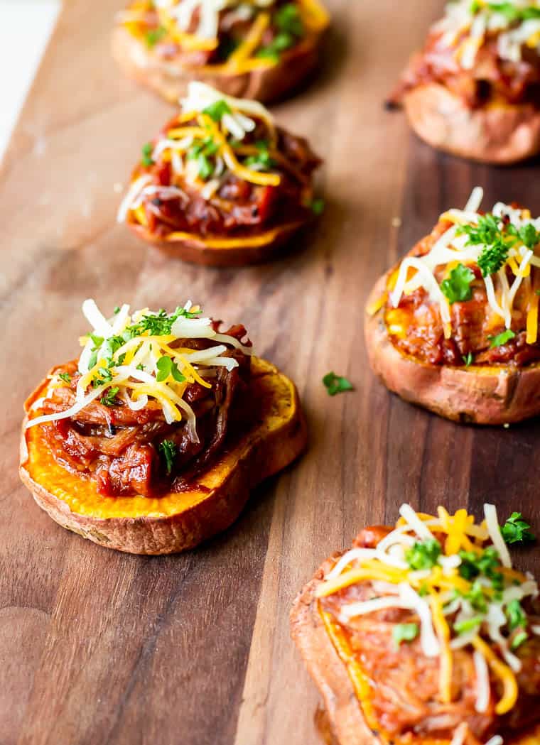 A wood board with 6 bbq pulled pork sweet potato rounds on it