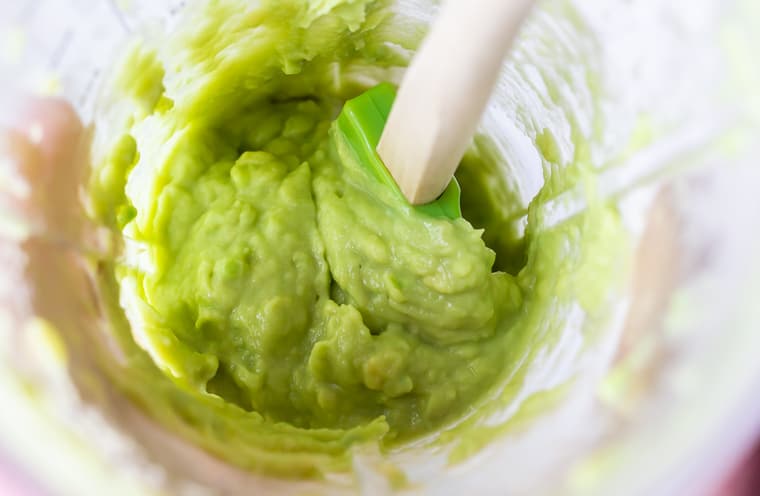 Avocado puree in a smoothie cup with a spatula