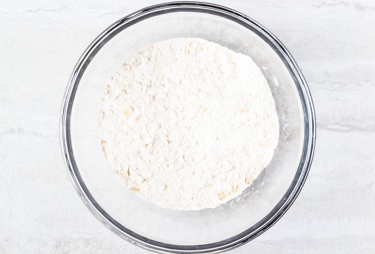 Dry ingredients for muffins in a glass bowl over a white background