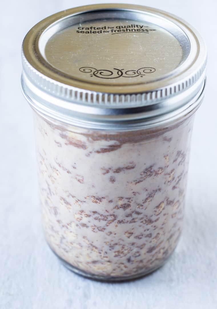 Overnight oats in a mason jar over a white background