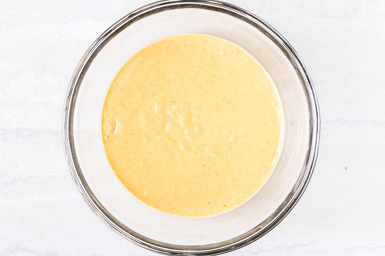Pumpkin pancake batter in a glass bowl over a white background