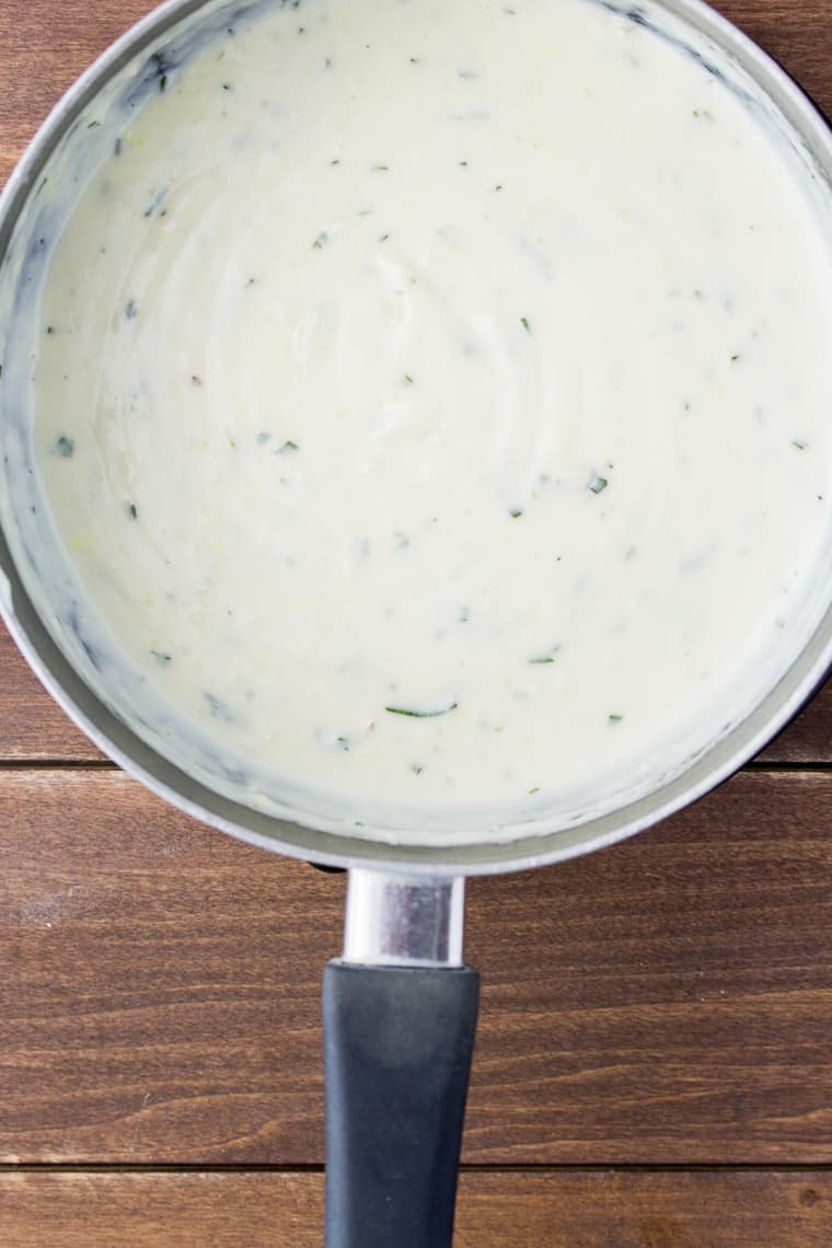 Rosemary Lemon Cream Sauce in a Saucepan over a wood background