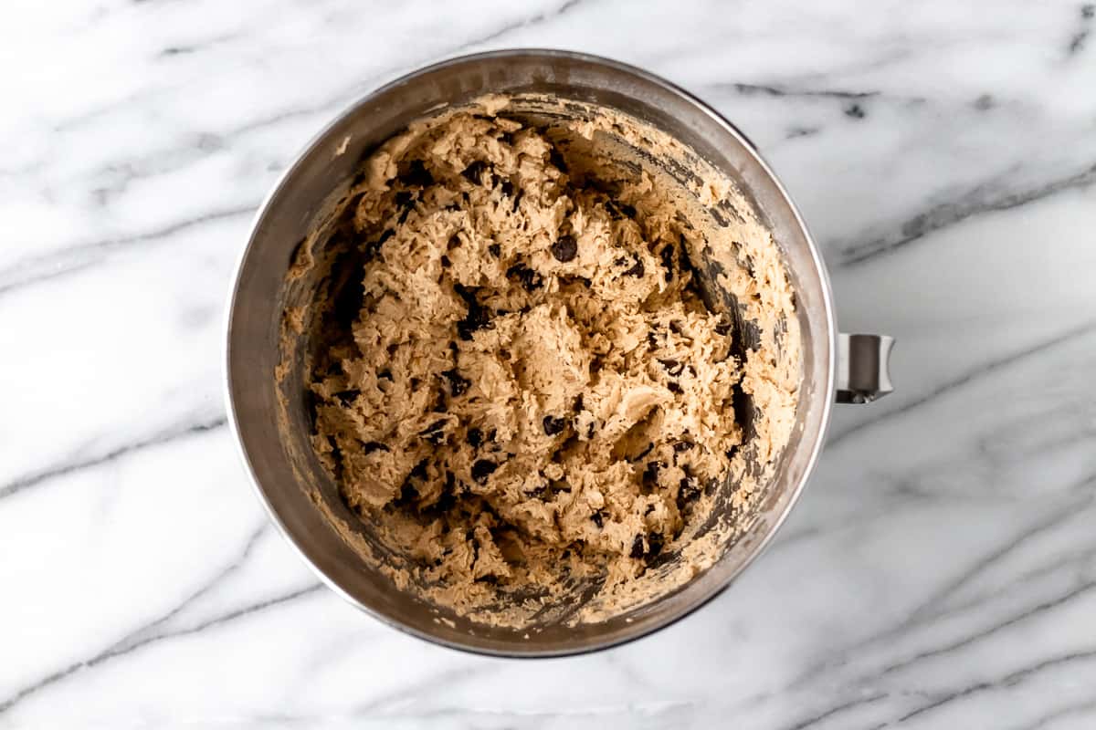 Chocolate chip cookie batter in a metal mixing bowl.