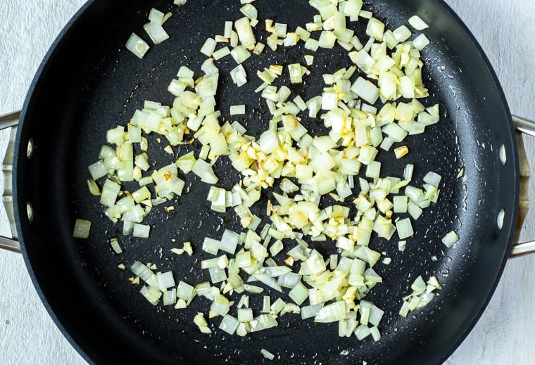 Onions and garlic cooking in a black pan