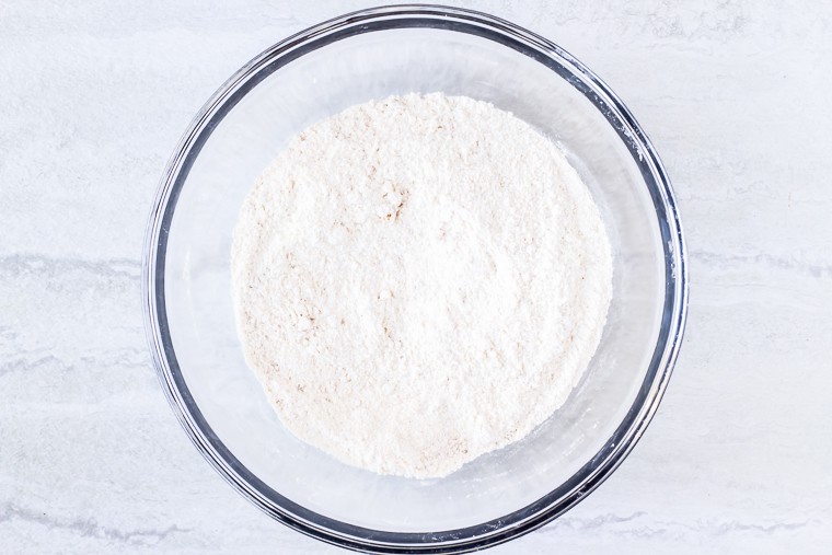 Dry ingredients in a glass bowl over a white background