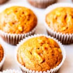 Pumpkin apple muffins scattered on a white background