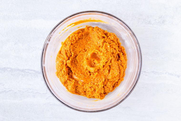 Pumpkin and wet ingredients in a glass bowl over a white background