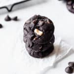 A stack of 3 dark chocolate hazelnut cookies over a white background