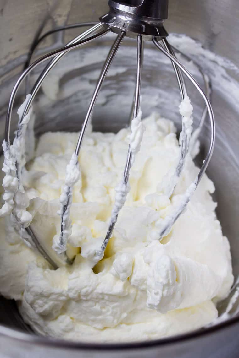 Close up of homemade whipped cream with a whisk in a metal bowl