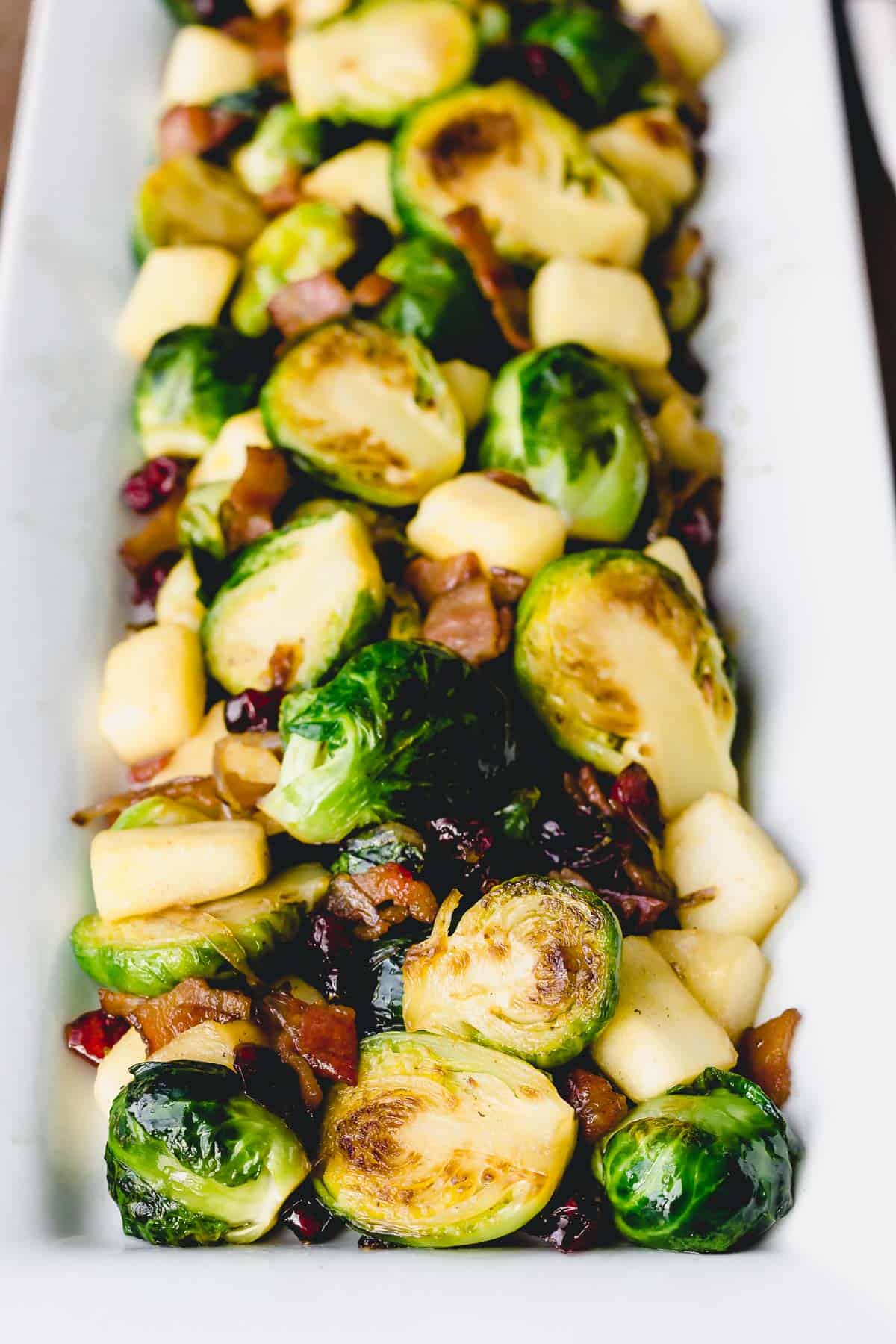 Close up of Bacon Cranberry Brussels Sprouts on a white serving tray