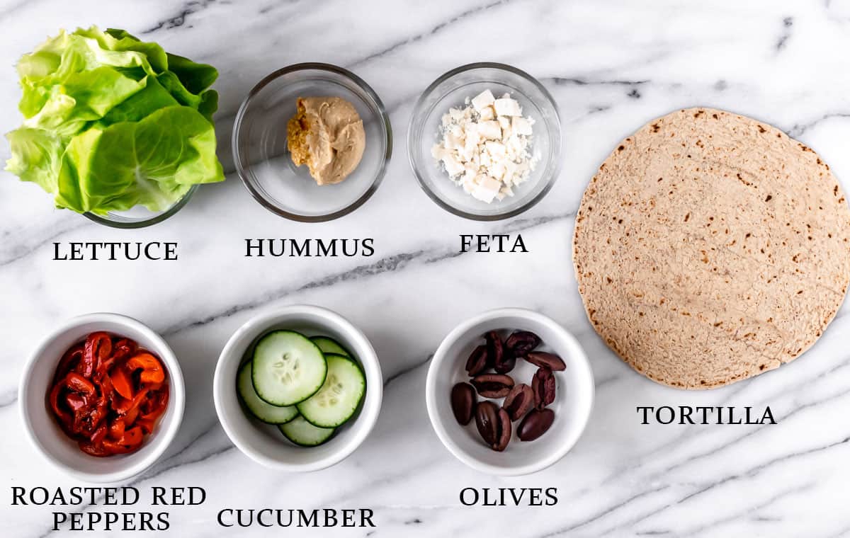 Ingredients to make a Greek veggie wrap on a marble background with text overlay.