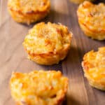 7 Baked Mac and Cheese Cups on a wood board