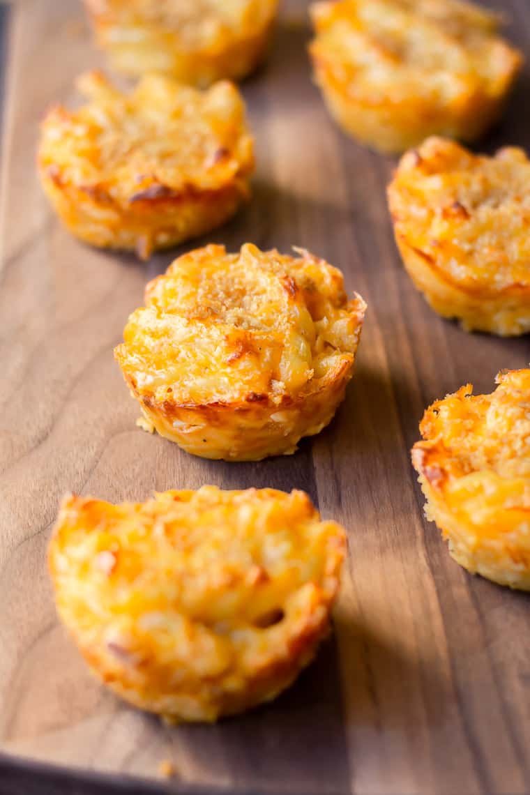 7 Baked Mac and Cheese Cups on a wood board