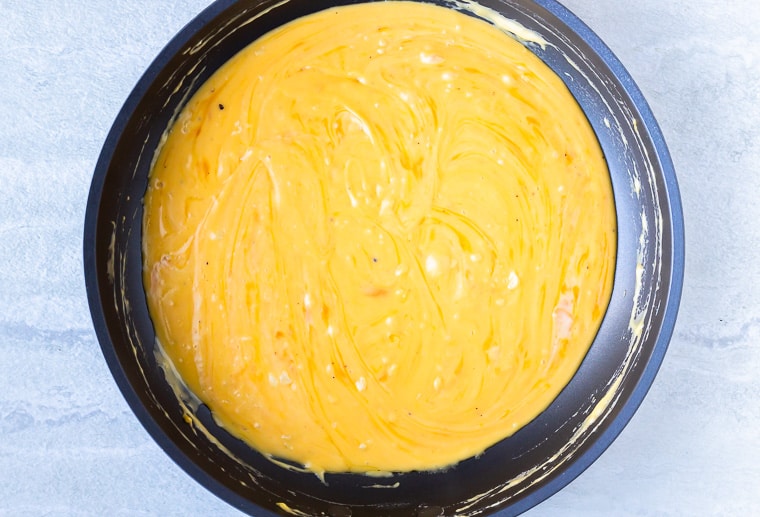 Cheese sauce for macaroni and cheese in a skillet over a white background