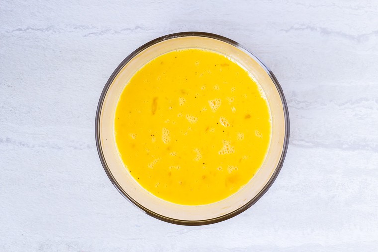 Scrambled eggs in a glass bowl over a white background