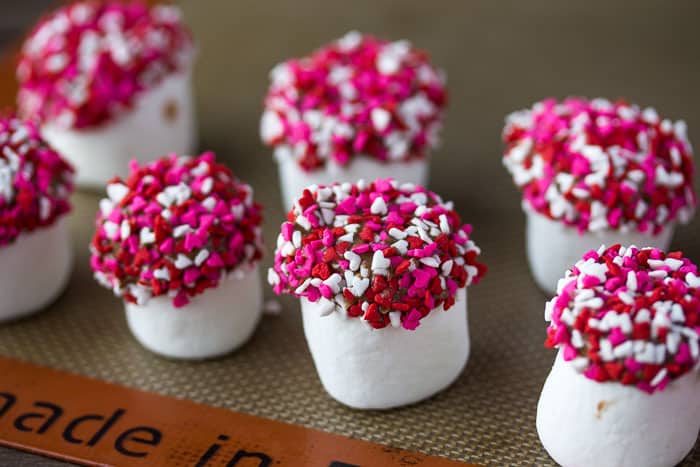Close up of 7 Candy Coated Marshmallows with pink and white heart sprinkles on them