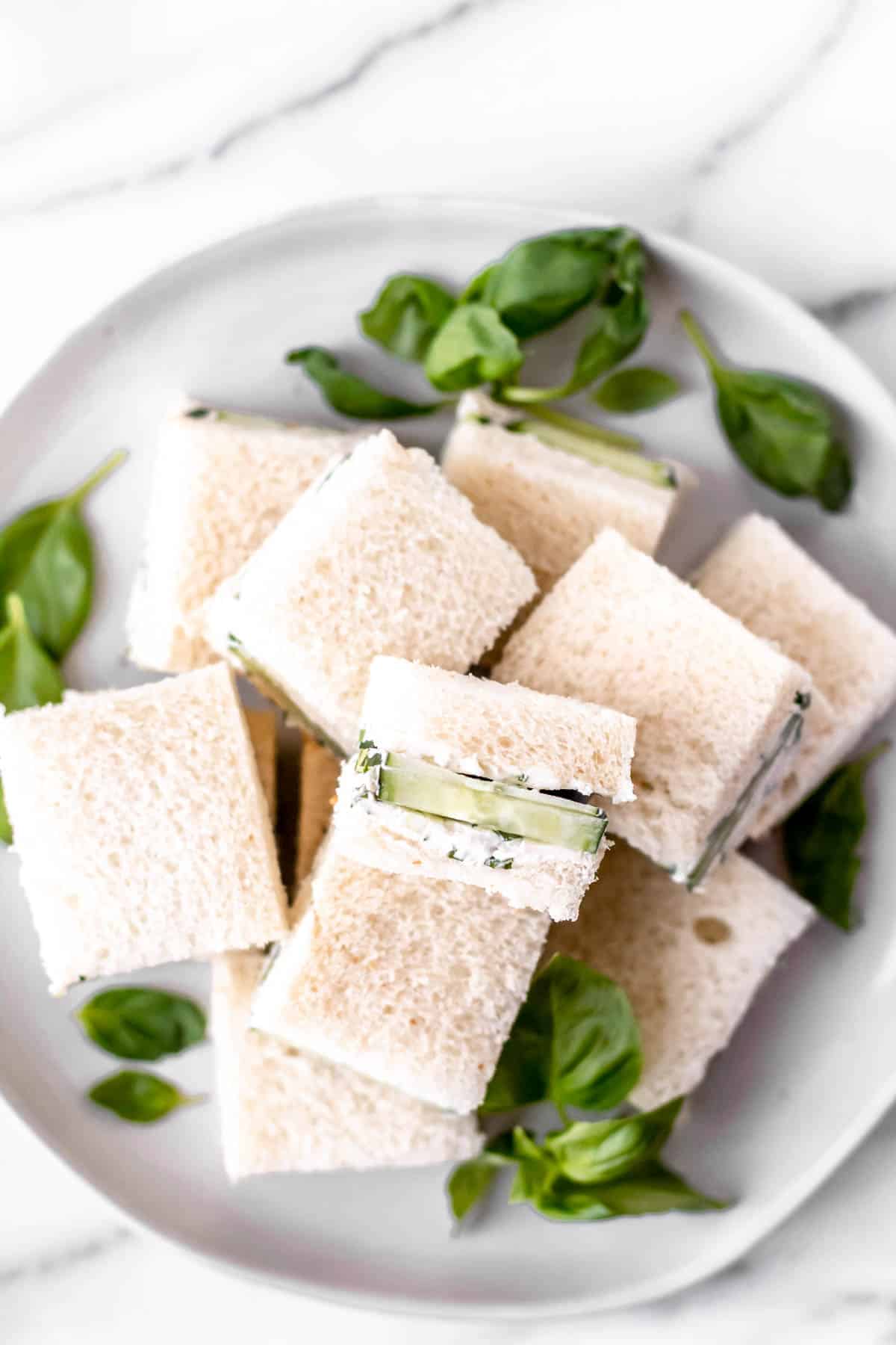 Cucumber tea sandwiches on a plate with one turned on its side to show the inside.