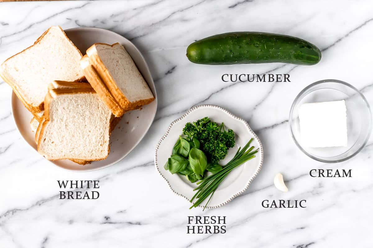 Ingredients needed to make cucumber tea sandwiches on a marble background with text overlay.