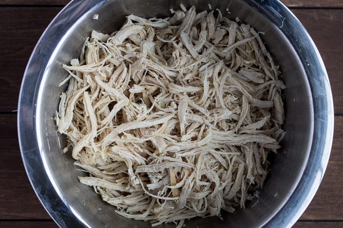 Shredded Chicken in a silver Bowl over a wood backdrop