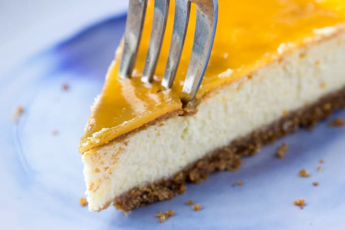 A Fork Cutting into a Piece of Vanilla Orange Cheesecake