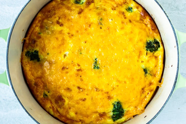 Baked Broccoli and cheese frittata in a Dutch oven over a white background