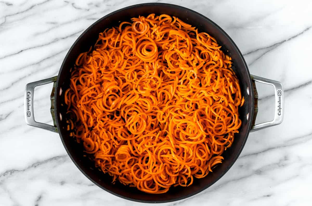 Carrot noodles cooking in a large skillet.