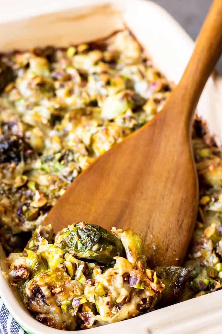 A scoop of Brussels Sprouts Gratin being lifted up with a wood server