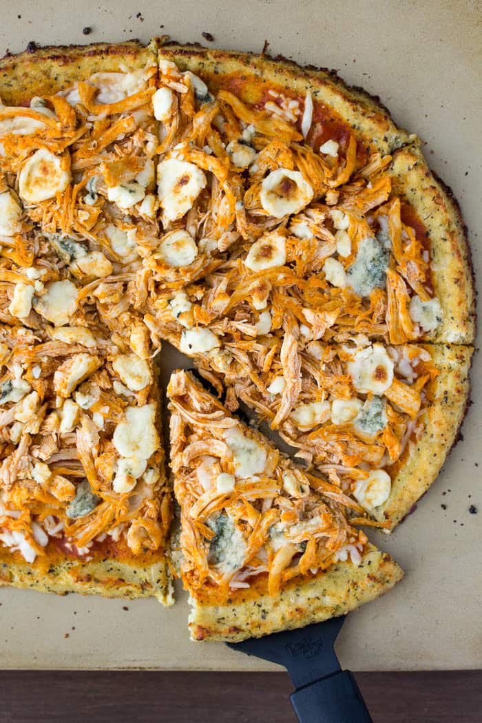 Finished Low Carb Buffalo Chicken Pizza on a Pizza Stone with a Slice Lifted Out
