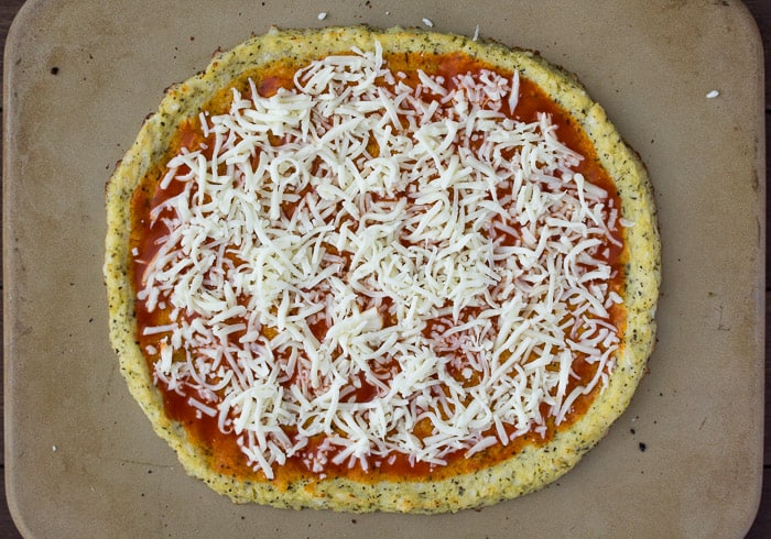 Cauliflower Pizza Crust with Buffalo sauce and Cheese Added on a pizza stone prior to baking