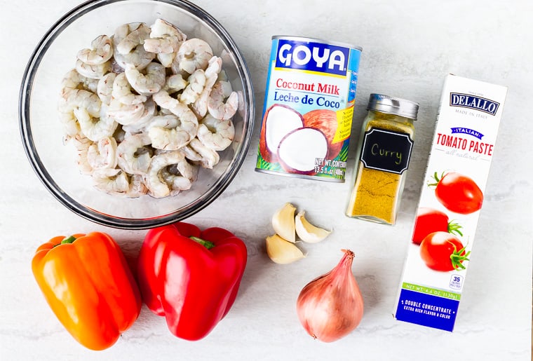 Ingredients needed to make coconut curry shrimp laying on a white background