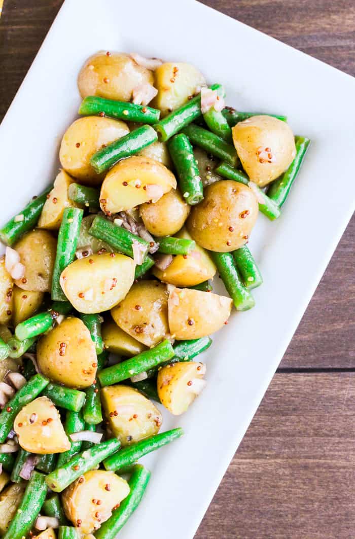 Close up of Green Bean Potato Salad on a Rectangular White Tray over a wood background