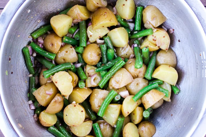 Green Beans and Potatoes with the Dressing Mixed In in a Silver Bowl