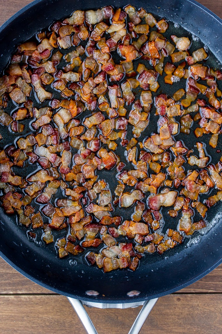 Overhead View of Chopped Bacon Cooked in a Black Skillet on a Wood Background