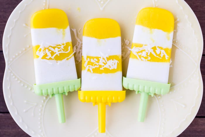 3 Mango Coconut Popsicles with Shredded Coconut on Them