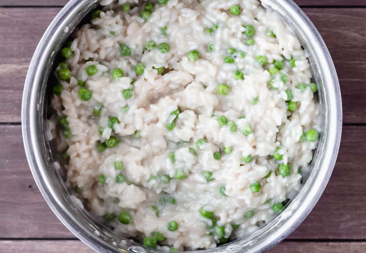 Risotto with peas in a silver pot over a wood background