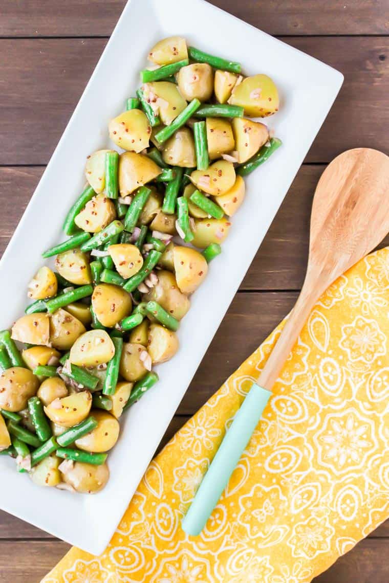Green Bean Potato Salad on a Rectangular Serving Tray with a Yellow Napkin and Wooden Spoon