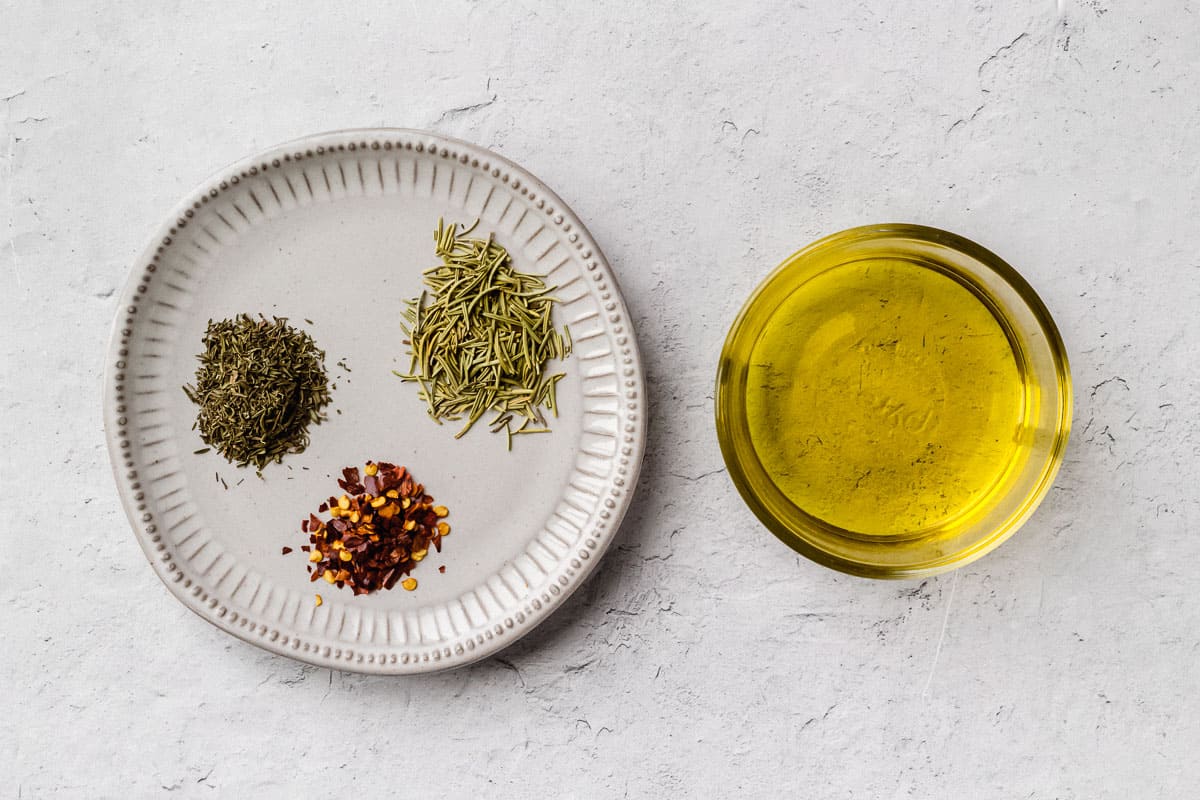 Ingredients for bread dipping oil with dried herbs on a white background