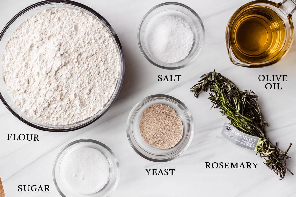 Ingredients to make homemade rosemary focaccia on a white background with labels