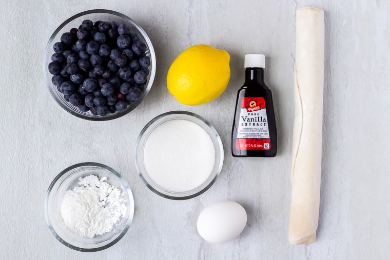 Ingredients needed to make blueberry hand pies on a white background