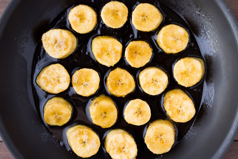 Raw Plantains Cooking in Coconut Oil in a black skillet