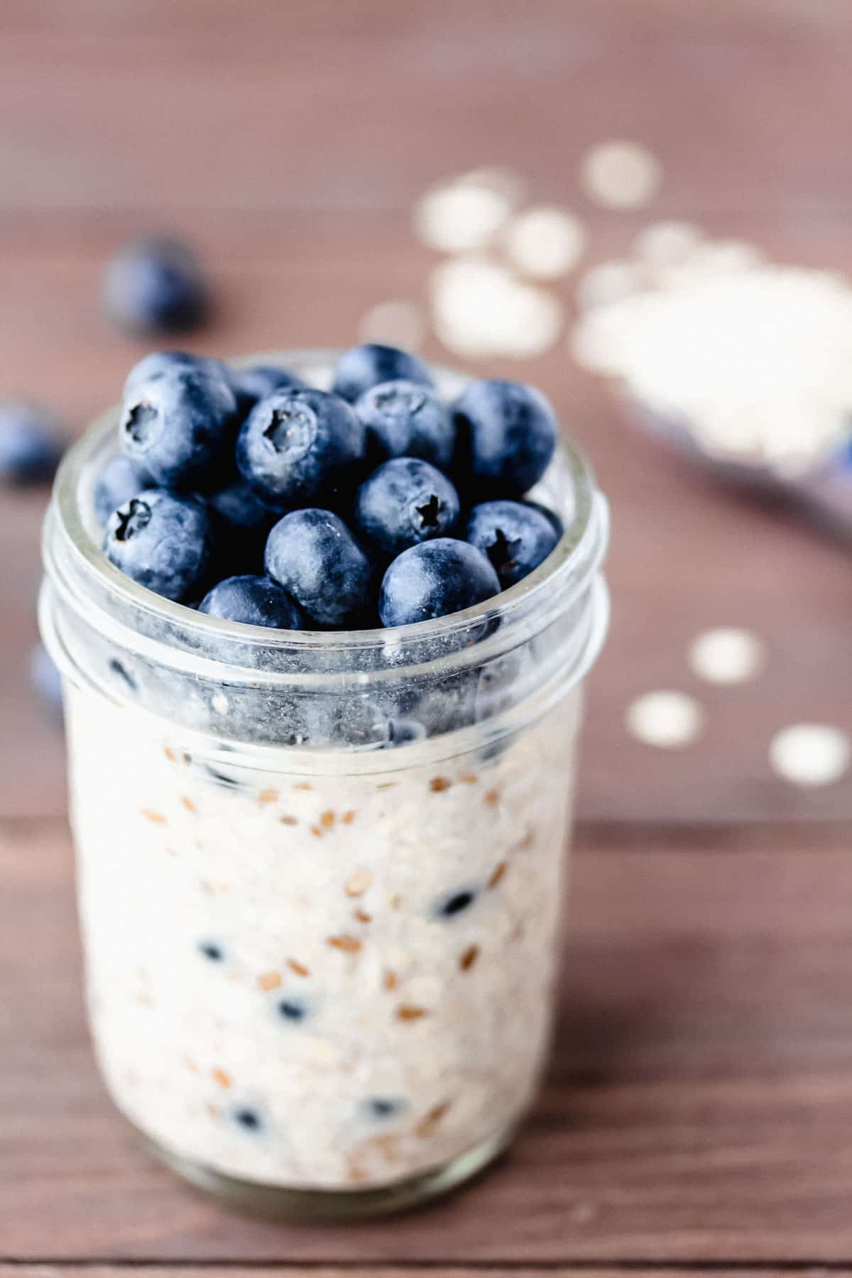 Blueberry overnight oats in a mason jar with a spoonful of oats behind it