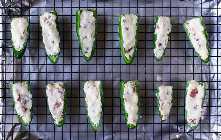 Jalapeno peppers stuffed with cream cheese on a baking rack