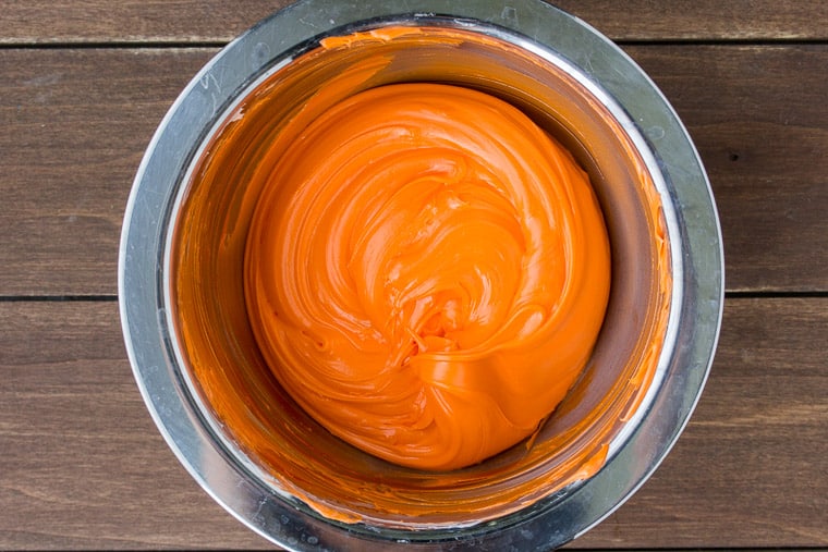 Orange Cake Icing in a Silver Bowl over a wood background