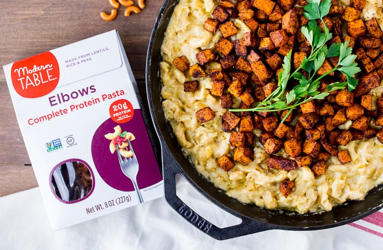 Chili Roasted Sweet Potato Mac and Cheese in a Cast Iron Skillet Next to a Box of Modern Table Pasta