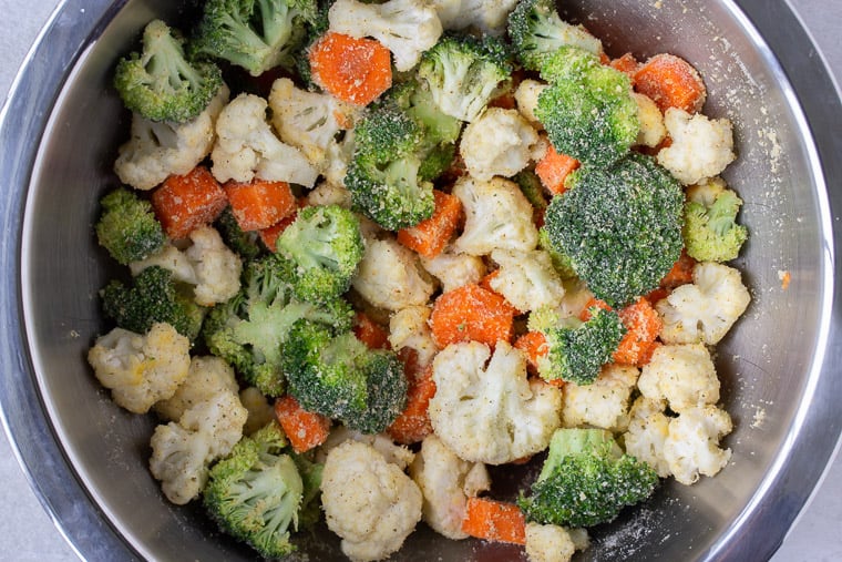 Broccoli, cauliflower and carrots tossed with Parmesan bread crumbs in a silver bowl