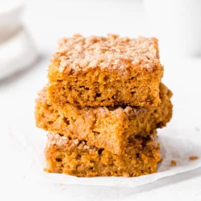 3 slices of pumpkin chai coffee cake stacked on top of each other with a white background
