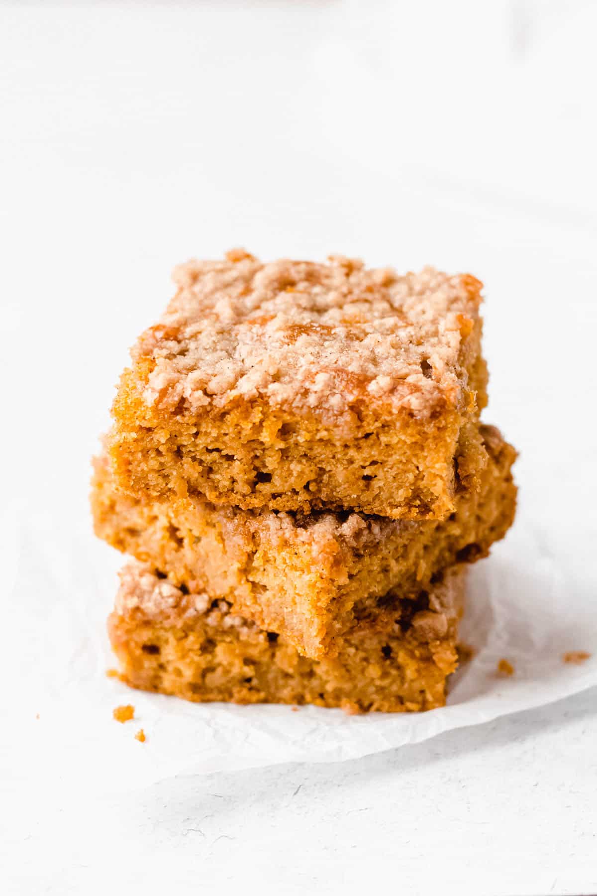 3 slices of pumpkin chai coffee cake stacked on top of each other with a white background