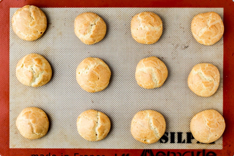 Baked Cream Puff Shells on a Silpat Lined Baking Sheet