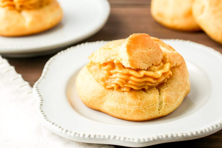 Pumpkin Spice Cream Puffs on a White Plates and more Cream Puff Shells in the Background