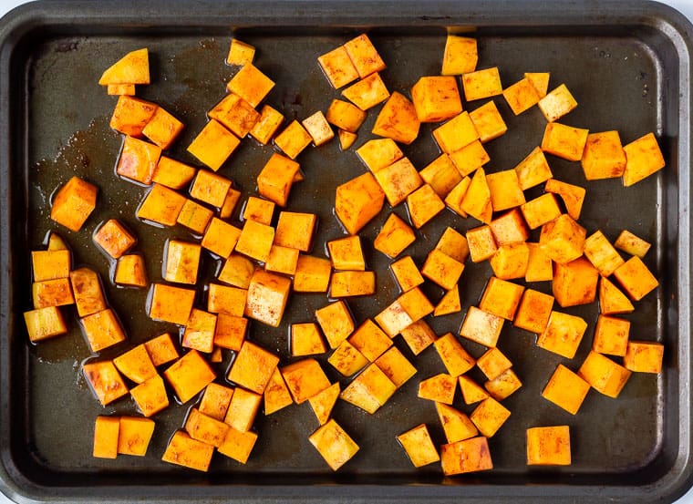 Butternut squash with cinnamon and maple syrup on a baking sheet